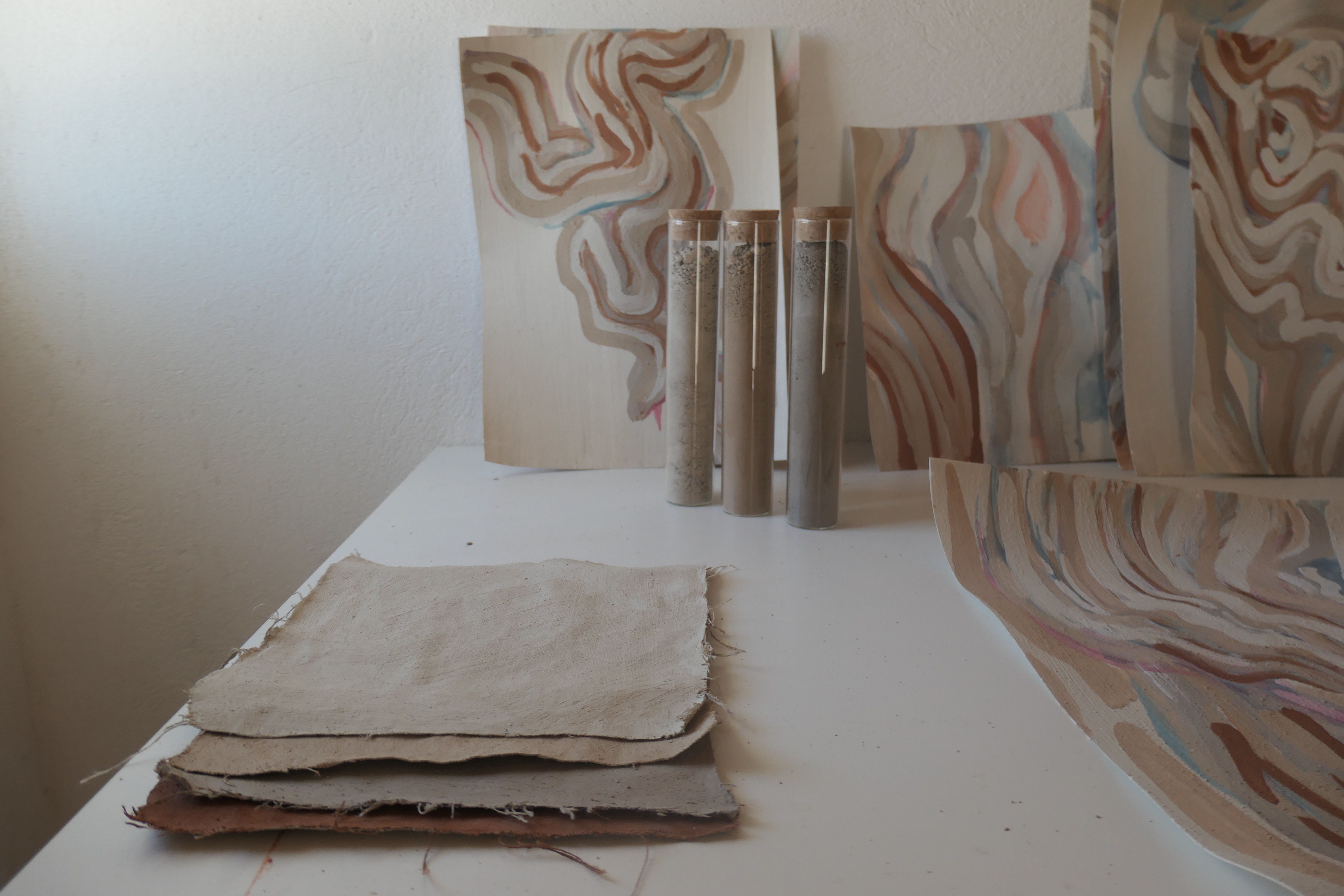 Works on paper and glass vials of soil on a studio table at Joya: AiR, 2024.